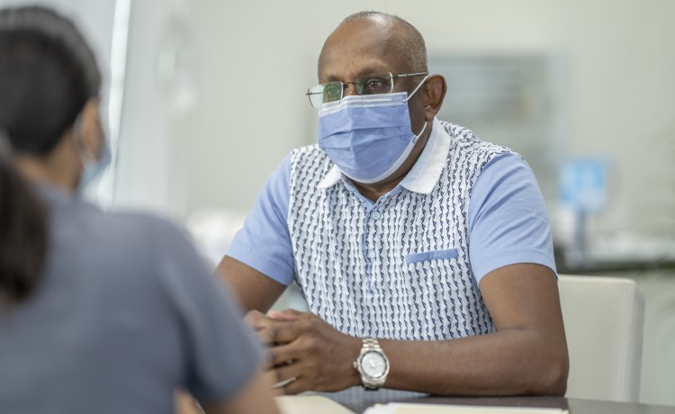 Un hombre habla con su médico sobre los síntomas duraderos de COVID-19.
