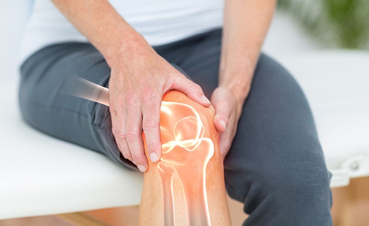 Man experiencing knee pain holds his knee.