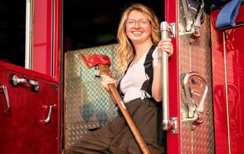 Grace R. stands on a firetruck with an ax after her successful scoliosis revision.