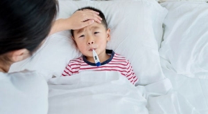 Mom feels forehead of child with a fever.
