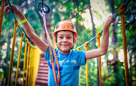 A boy wears a helmet while completing a ropes course.