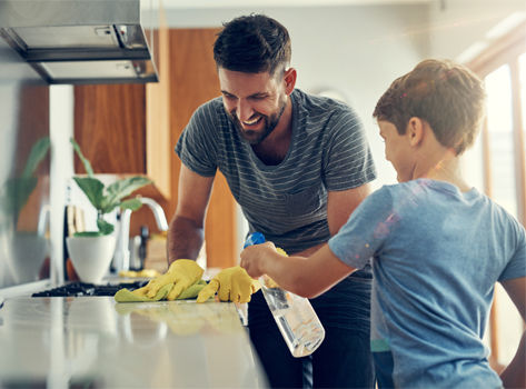 A man and his son clean their home of allergens using cleaning products.