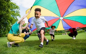 little kids running beneath a play parachute 