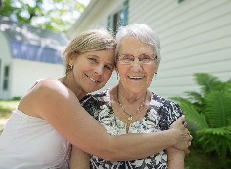 A mature woman hugs her aging mother.