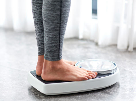 A close up of a woman's feet standing on a weight scale.
