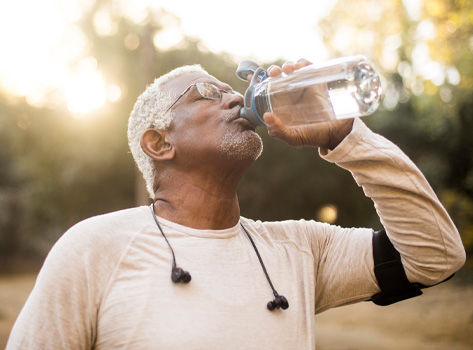 Un hombre afroamericano de edad avanzada disfrutando de agua refrescante después de un entrenamiento