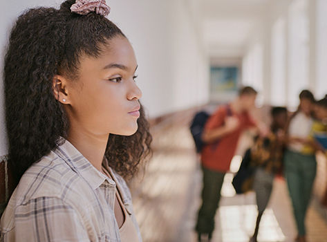 A teenage girl, at school, looks anxious.