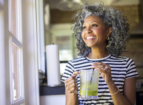 An African-American woman prepares to drink a green juice smoothie.
