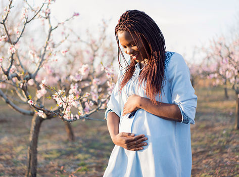 A pregnant black woman cradles her belly.