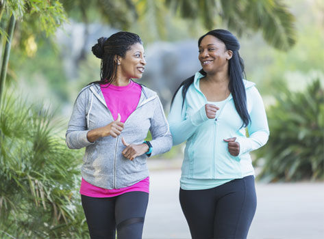 Two women take a brisk walk together to get their steps in.