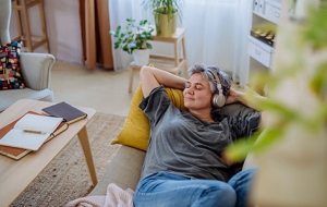 mujer de mediana edad relajándose en el sofá con auriculares puestos