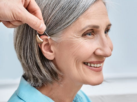 A mature woman is fitted for a hearing aid.