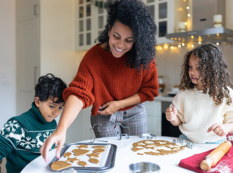 A mom and two children make gingerbread cookies.