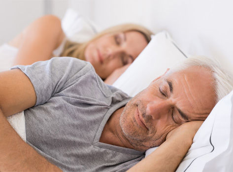 Middle-aged couple sleeps soundly side-by-side.