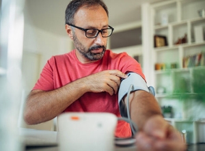 Foto de un hombre preparándose para medirse la presión sanguínea en casa