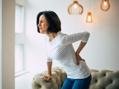 A woman with back pain clutches her lower back.
