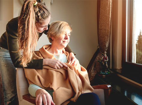 A female dementia patient is comforted by her daughter.