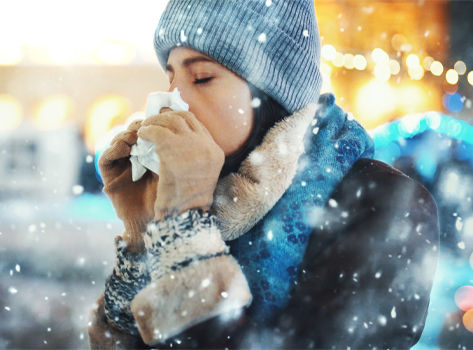 Young woman blows her nose in the snow.