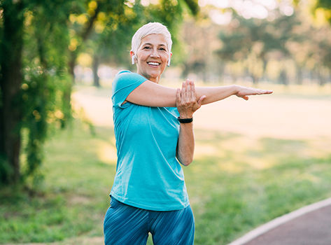 A senior cancer survivor stretches before exercise.