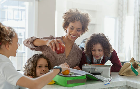Mother helping daughters to pack lunches.
