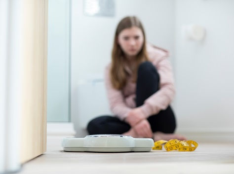 A young girl stares at her bathroom scale.