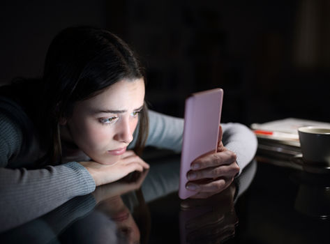 Teenager sitting in the dark staring at her phone