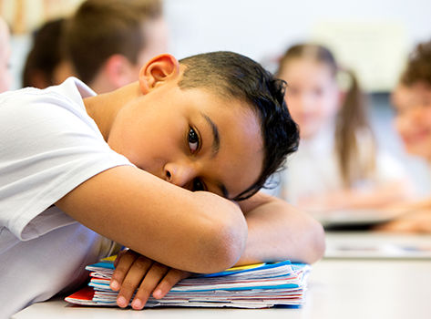 Young boy laying his head on his desk