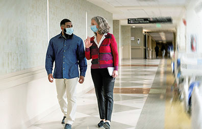 Patient walking down the hall with Glasser Patient Navigator.