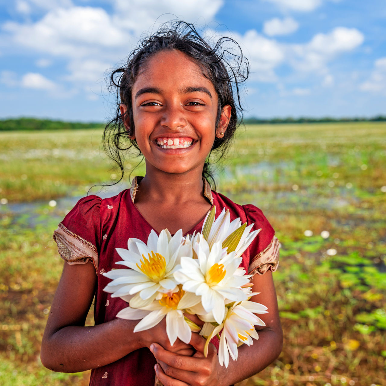 Una niña feliz sostiene un montón de margaritas.