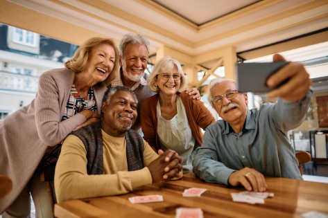 Sociable group of seniors smile and take selfie at a retirement home.