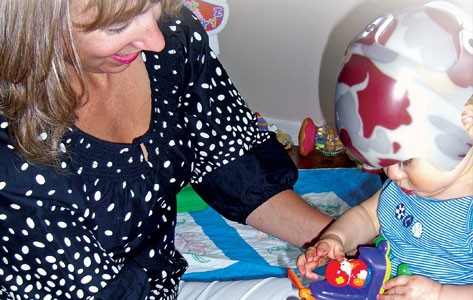 Una madre jugando con su hijo que está siendo tratado por un trastorno craneofacial.