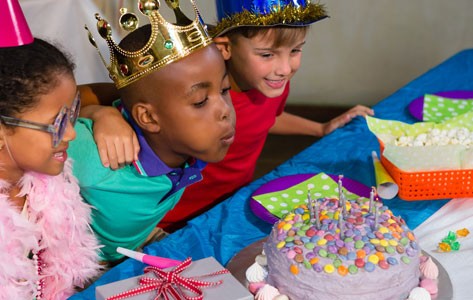 Unos niños apagan las velas de un pastel de cumpleaños