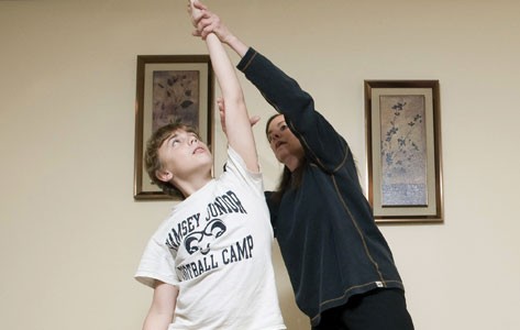 Una fisioterapeuta ayuda a un niño a estirar el brazo