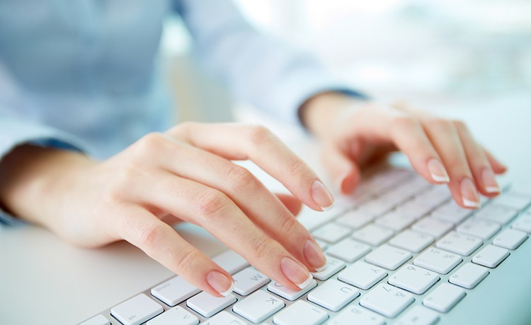 Mujer escribiendo en un teclado de computadora