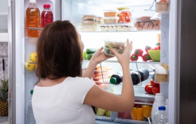 Una mujer saca alimentos saludables de su refrigerador.