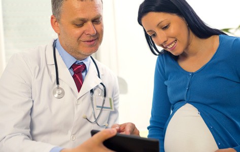 Un ginecólogo y obstetra consulta la historia clínica con una paciente embarazada