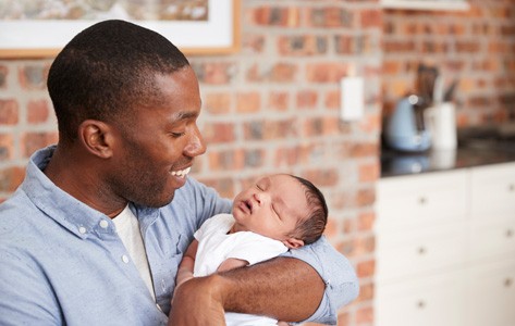 Padre afroamericano sosteniendo a un bebé recién nacido