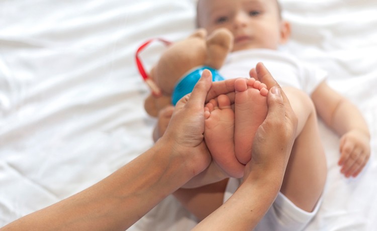 A newborn's mom caresses his feet.
