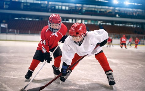 dos niños luchan por un disco en un juego de hockey sobre hielo juvenil