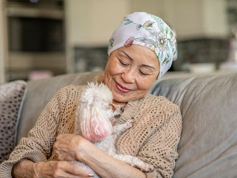 Paciente asiática de cuidados paliativos acurrucada con su perro.