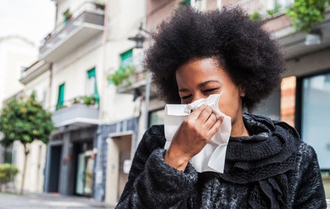 Un niño afroamericano con alergia estornuda
