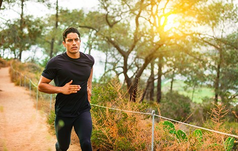 Hombre corriendo en un sendero por el bosque