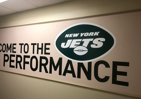 La imagen es el logotipo de los NY Jets en la pared del Performance Lab.