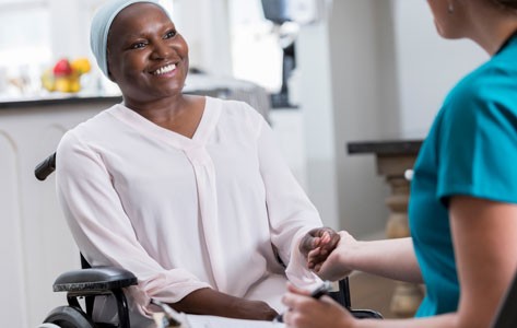 Una enfermera de hospicio visita a una paciente en silla de ruedas