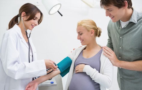 Una médica le toma la presión arterial a una madre embarazada