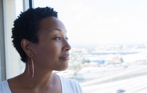 Mujer afroamericana mirando por la ventana