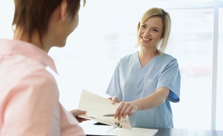 Una enfermera entrega documentos a una paciente