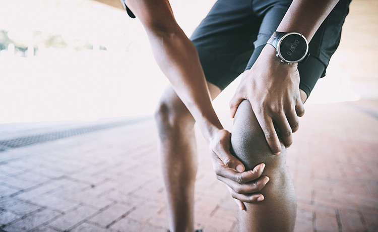 male athlete holding knee in pain
