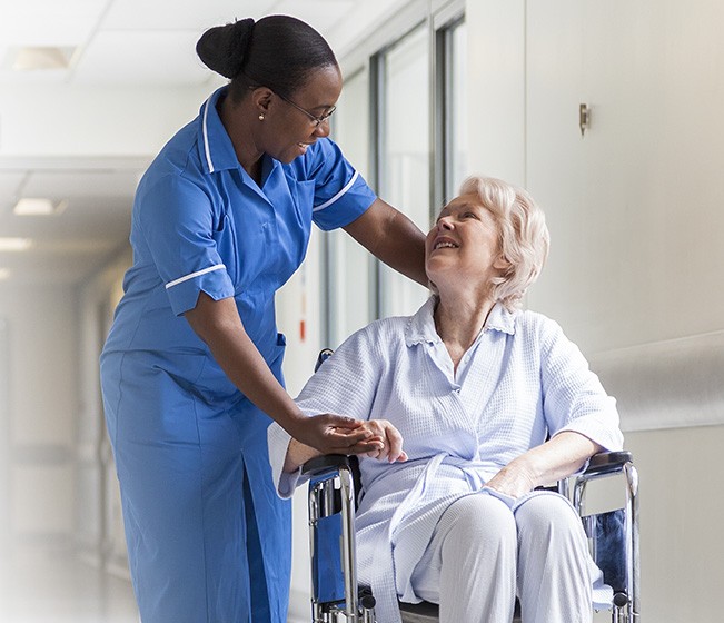 Camillera del hospital ayuda a una mujer en silla de ruedas
