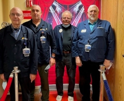 Four male volunteers stand together in their Morristown Medical Center volunteer uniforms.